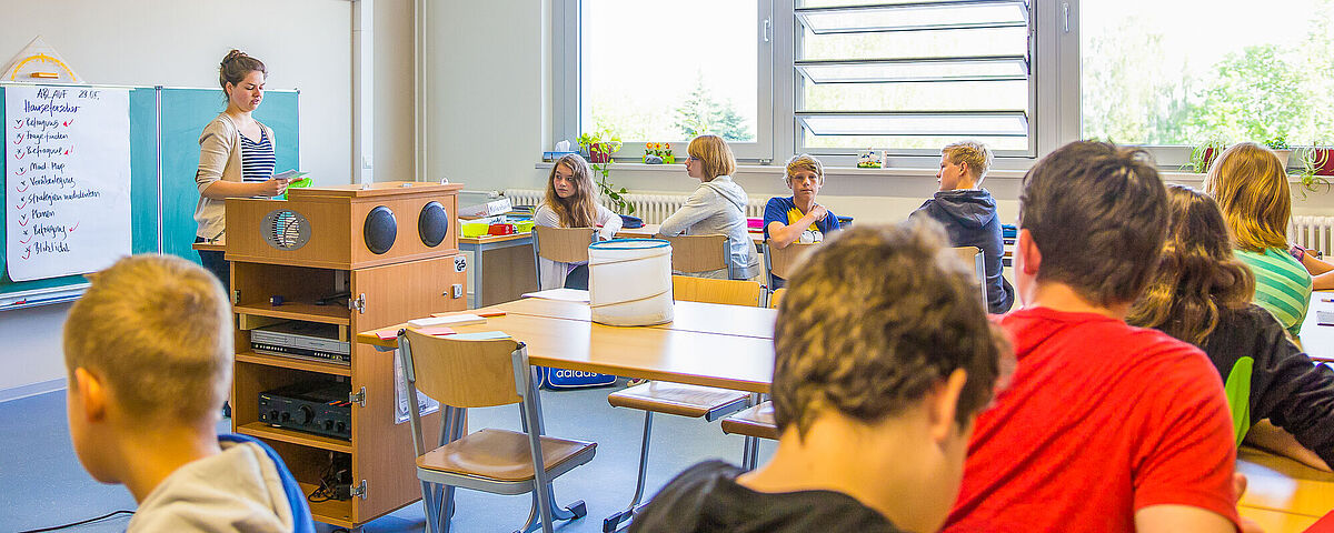 Kinder in einer Schulklasse hören aufmerksam der Dozierenden zu.